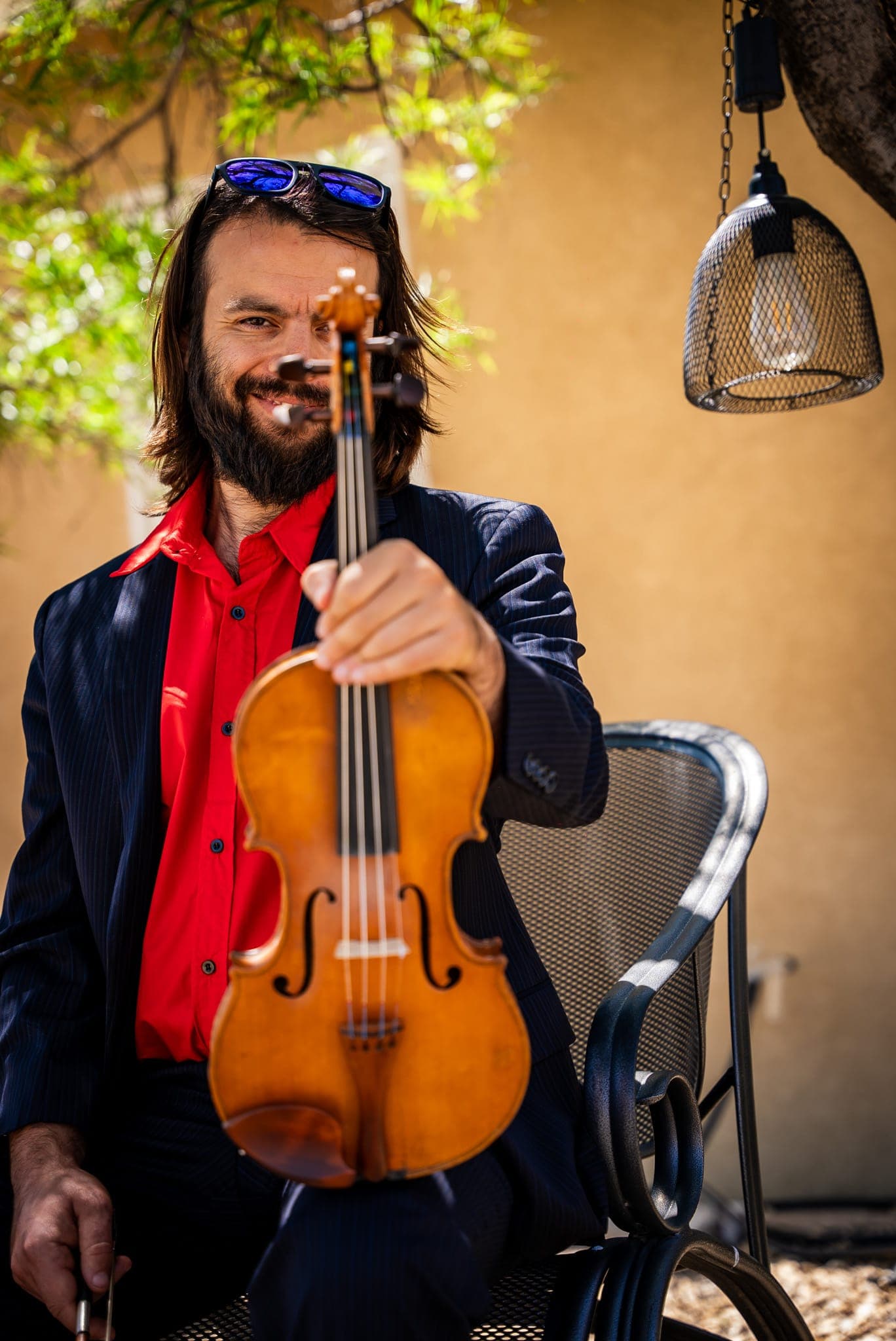 Daniel in a black tuxedo playing violin against a wooden wall